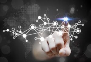 A hand pointing at a glowing digital node on a network of interconnected dots with a global map background representing technology.