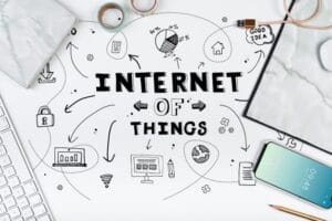 Top view of Internet of Things concept sketched on paper with connected icons, smartphone, and office accessories around it.